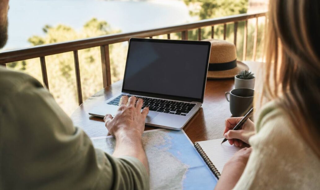 Stel dat reisdetails vergelijkt op een laptop en notities maakt voor de volgende vakantie