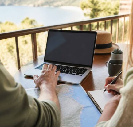 Stel dat reisdetails vergelijkt op een laptop en notities maakt voor de volgende vakantie